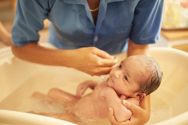Casal dando banho no recém-nascido na banheira