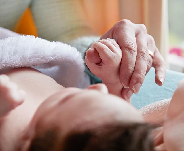 Segurando as mãos de um bebê deitado